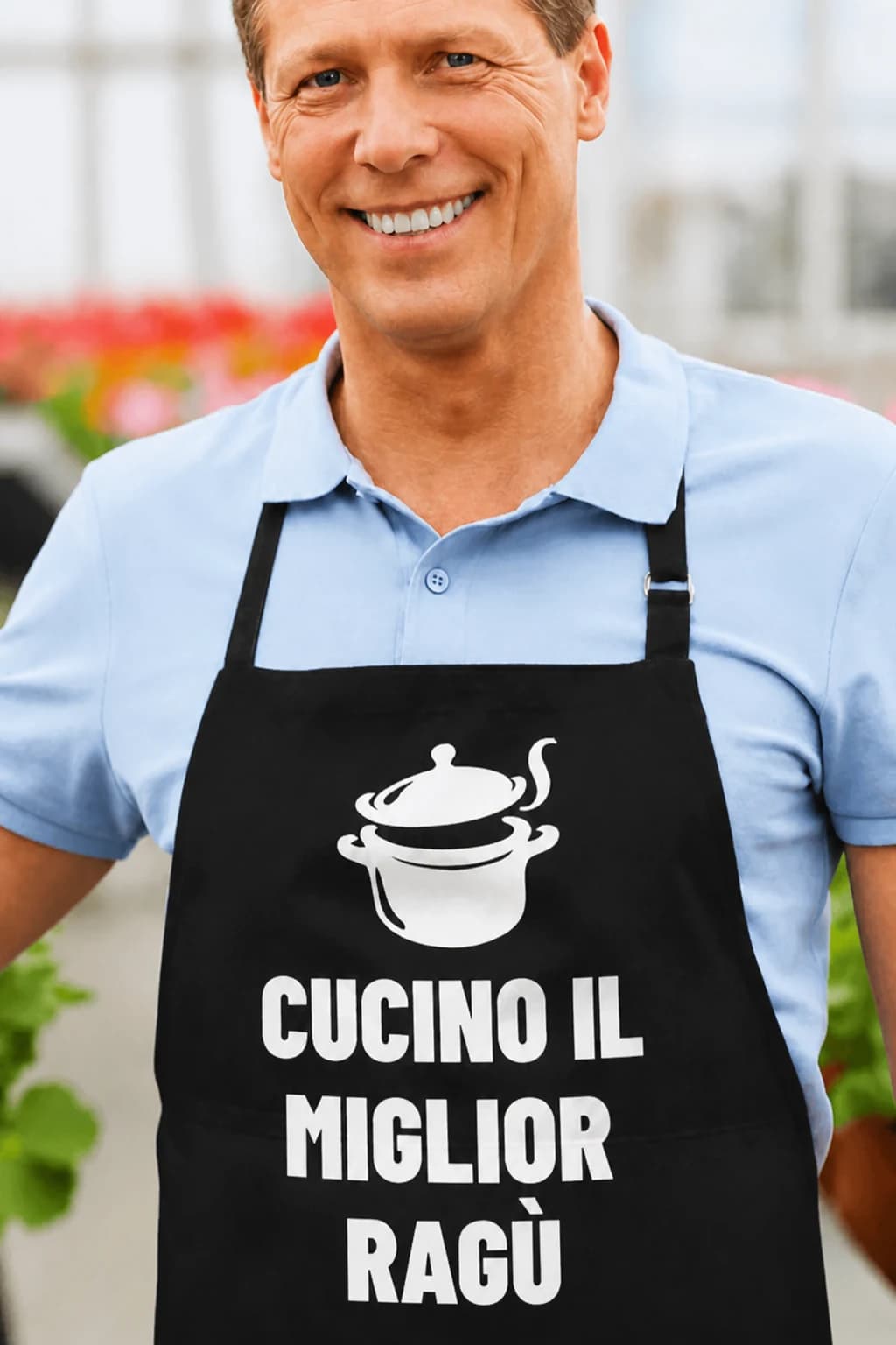 Uomo sorridente con grembiule nero con pentola fumante e scritta bianca “Cucino il miglior ragù”