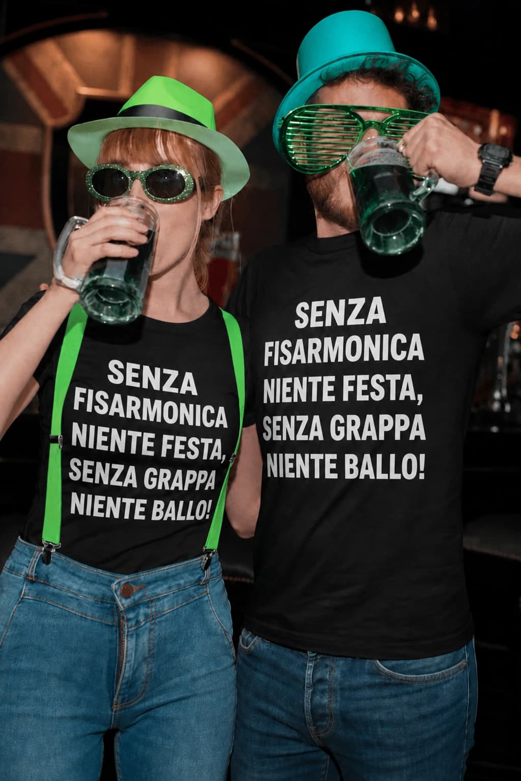 Coppia con cappelli verdi e boccali, magliette nere con scritta “Senza fisarmonica niente festa” in bianco