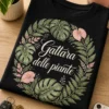 T-shirt donna con illustrazione botanica raffinata e scritta Gattara delle piante, con foglie di monstera e felci in cornice ovale verde salvia e blush.